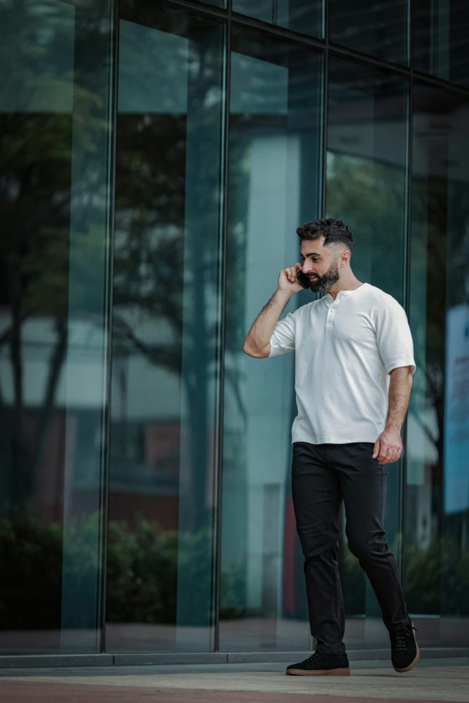 Man in white shirt talking on phone outside building